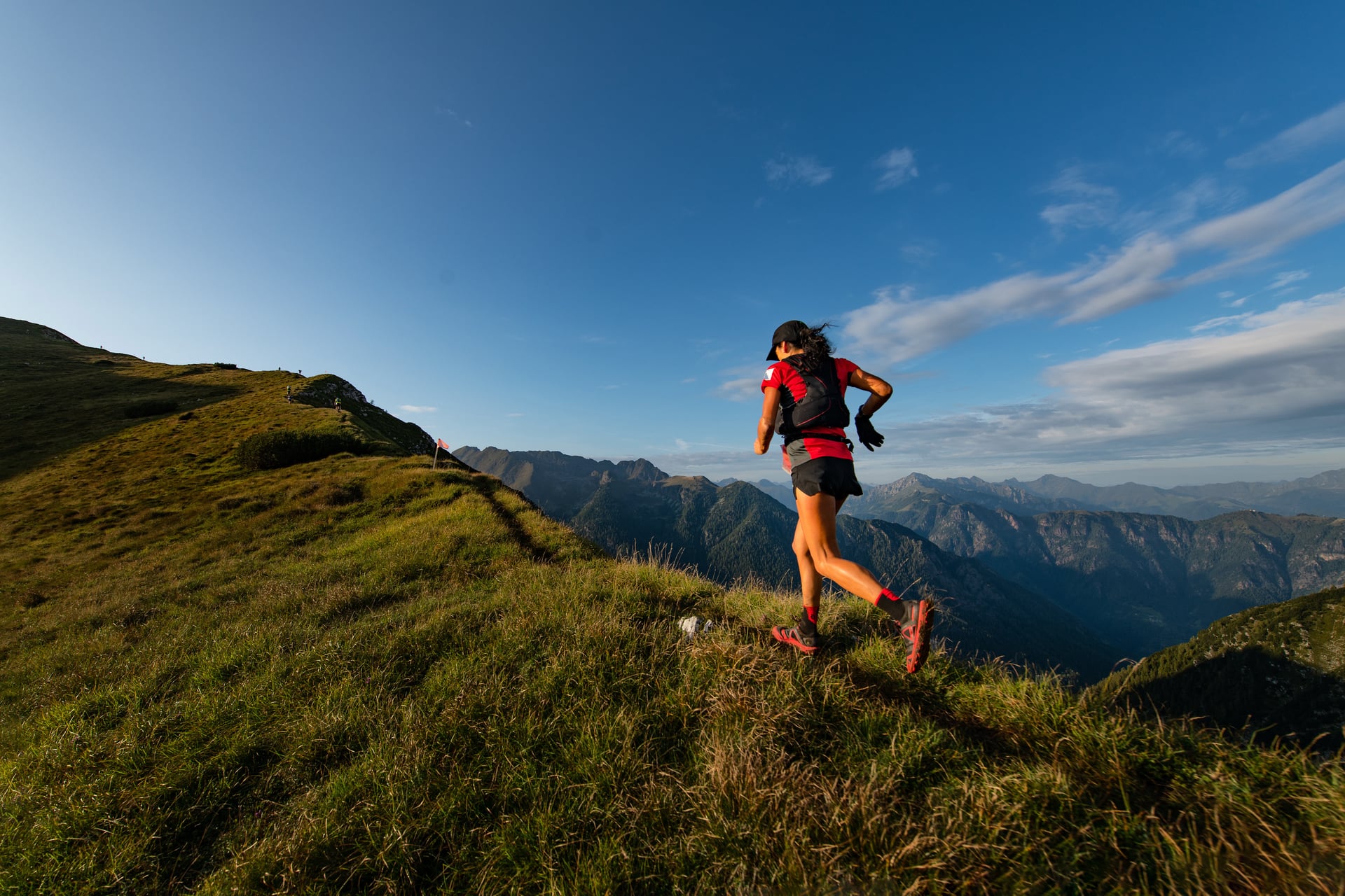Trail runner in a hydration vest on a mountain ridge at golden hour